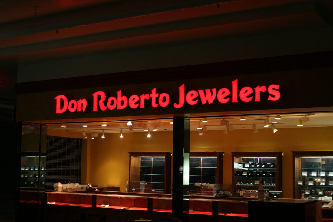 Illuminated channel letter sign on a Fresno storefront at dusk